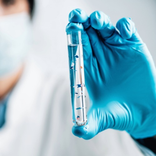 Close-up of a test tube containing microplastic particles, representing scientific research on plastic pollution.