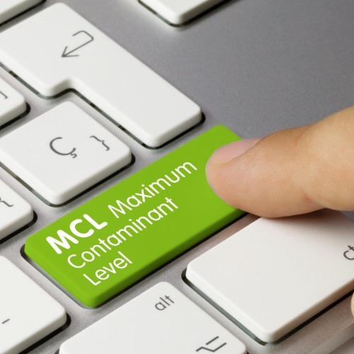 Finger pressing a green keyboard key labeled &ldquo;MCL Maximum Contaminant Level,&rdquo; representing EPA drinking water standards used to evaluate tap water compliance.