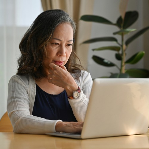 Woman using a laptop to look up information about her local drinking water quality and Consumer Confidence Report.