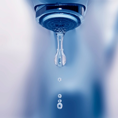 Close-up of a dripping faucet illustrating water waste and the importance of fixing leaks