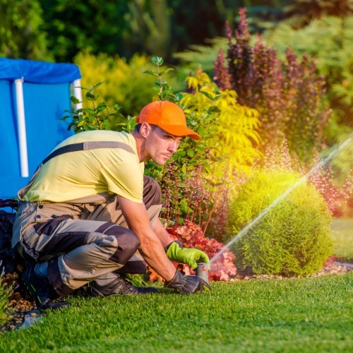 Person adjusting a lawn sprinkler system to improve irrigation efficiency and conserve water