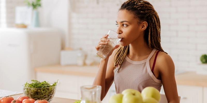 Person drinking a glass of water at home to represent safe and healthy drinking water